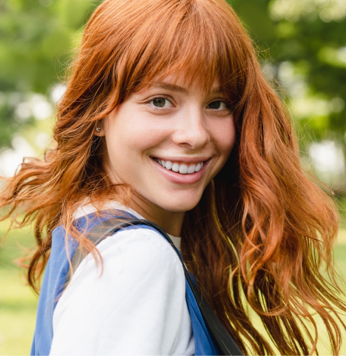 Red-head with long hair turning around outside. 
