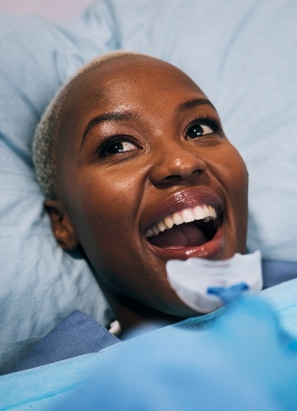 Happy female smiling lying down getting prepped for oral surgery.