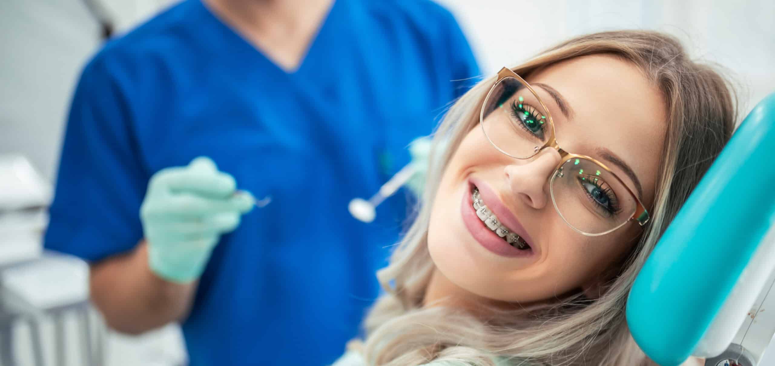 Young person with blonde highlights and glasses, smiling with braces. 
